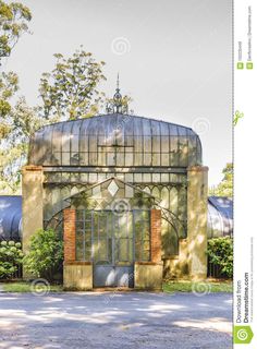 an old glass house surrounded by trees and bushes in the sunbeams stock photo - image