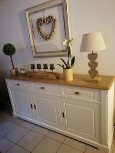 there is a white cabinet with two vases on it and a lamp next to it