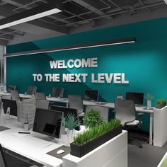 an office with desks, computers and plants on the wall that says welcome to the next level