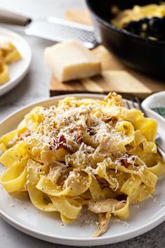 pasta with chicken and parmesan cheese on a plate next to a skillet