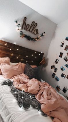 an unmade bed with pink sheets and blankets on it in front of a hello sign