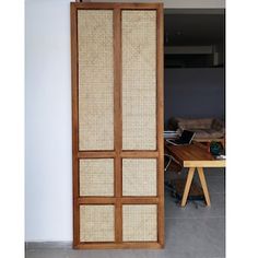 a room divider made out of wood and rattan weaves, with a table in the background