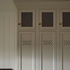 an empty bench in front of two tall white cupboards with metal doors on each side