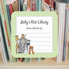 a baby's first library sign in front of bookshelves with giraffes and zebras