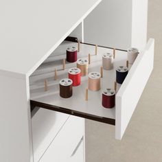 several spools of thread are on the shelf in front of an open cabinet