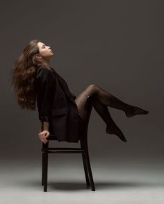 a woman sitting on top of a chair with her legs crossed and wearing black stockings