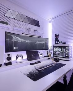 a white desk topped with a computer monitor and keyboard next to a speaker set up on top of it