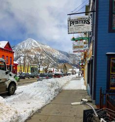 a city street with snow on the ground and mountains in the backgrouds