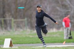 a woman is throwing a frisbee in the park while another man looks on