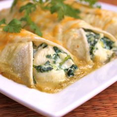 three tortillas with spinach and cheese in a white dish on a wooden table