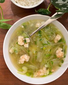 a white bowl filled with soup next to another bowl full of rice and veggies