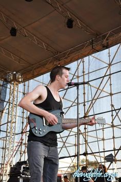 a man standing on top of a stage holding a guitar