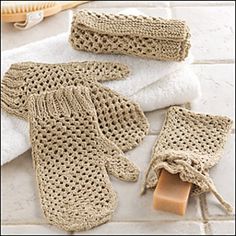 two knitted mittens and gloves sitting on top of a white tile floor next to a wooden brush