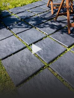 a chair sitting on top of a grass covered field next to a stone patio floor