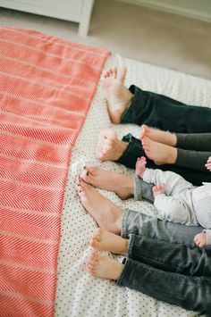 two people sitting on a bed with their feet up and one person holding a baby