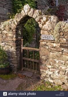 an old stone gate with the word garden written on it and surrounded by greenery