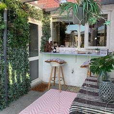 an outdoor bar with plants and potted plants on the outside wall, in front of a building