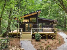 a small cabin in the woods with stairs leading up to it's deck area