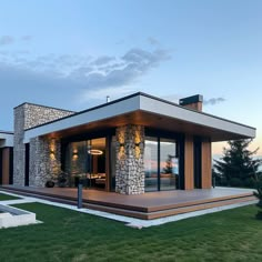 a modern house with stone and wood accents on the front porch, sitting in grass