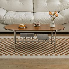 a coffee table sitting on top of a checkered rug in front of a white couch