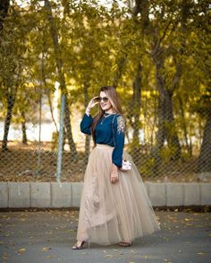 a woman in a blue top and beige tulle skirt is posing for the camera