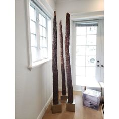 two tall wooden sculptures sitting on top of a hard wood floor next to a window