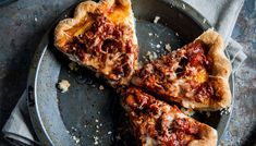 three slices of pizza sitting on top of a metal plate next to a knife and fork