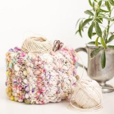 a crocheted pot holder next to a ball of yarn and a planter