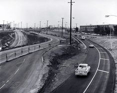 an old car driving down the road in black and white