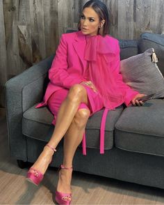 a woman sitting on top of a couch in a pink dress and high heeled shoes