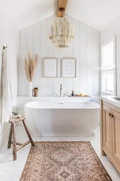 a large white bath tub sitting next to a wooden stool