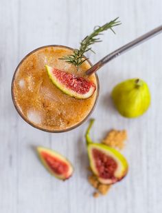 a grapefruit cocktail garnished with rosemary and sliced figs on a white table