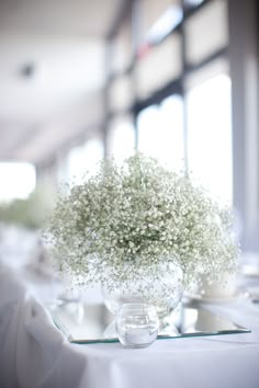 baby's breath in a glass vase on a table at a banquet or wedding