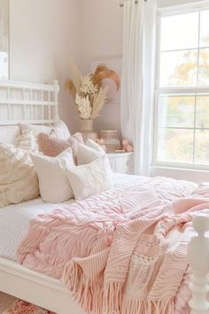 a white bed topped with pink blankets and pillows