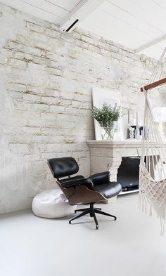 a hammock hanging from the ceiling in a room with white walls and furniture