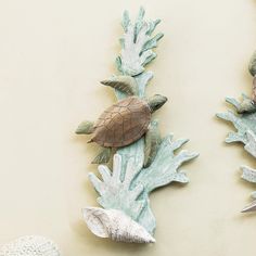 two sea turtle wall hangings on the side of a wall with seashells attached to them