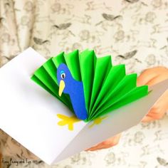 a person holding a paper bird on top of a piece of white paper in their hand