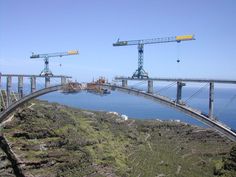 two cranes are on the side of a bridge