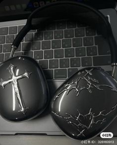 a pair of black headphones sitting on top of a laptop computer next to a cross