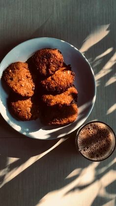 some fried food on a white plate next to a cup of coffee