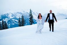 a bride and groom holding hands in the snow on top of a mountain at their wedding