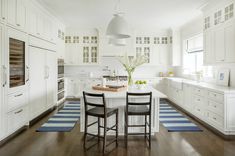 a large kitchen with white cabinets and blue rugs on the hardwood floored floor