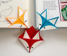 two folded origami animals sitting on top of an open book