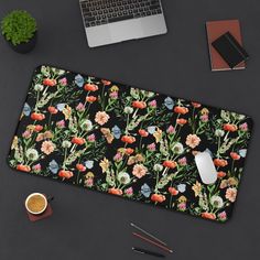 a computer mouse pad with flowers on it next to a cup of coffee and a laptop