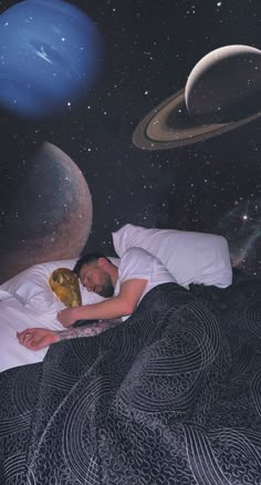 a man is sleeping in bed with planets on the wall behind him and an image of saturn