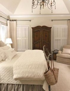 a bedroom with a bed, chair and chandelier