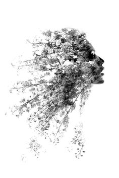 a black and white photo of a woman's face with flowers in her hair