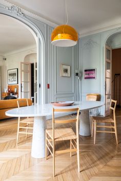 a table and chairs in a room with wood flooring on one side and an archway to the other