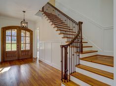 a staircase with wooden handrails leading up to an open door on the second floor