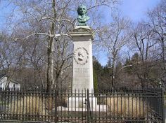 there is a statue in the middle of this fenced area with trees behind it